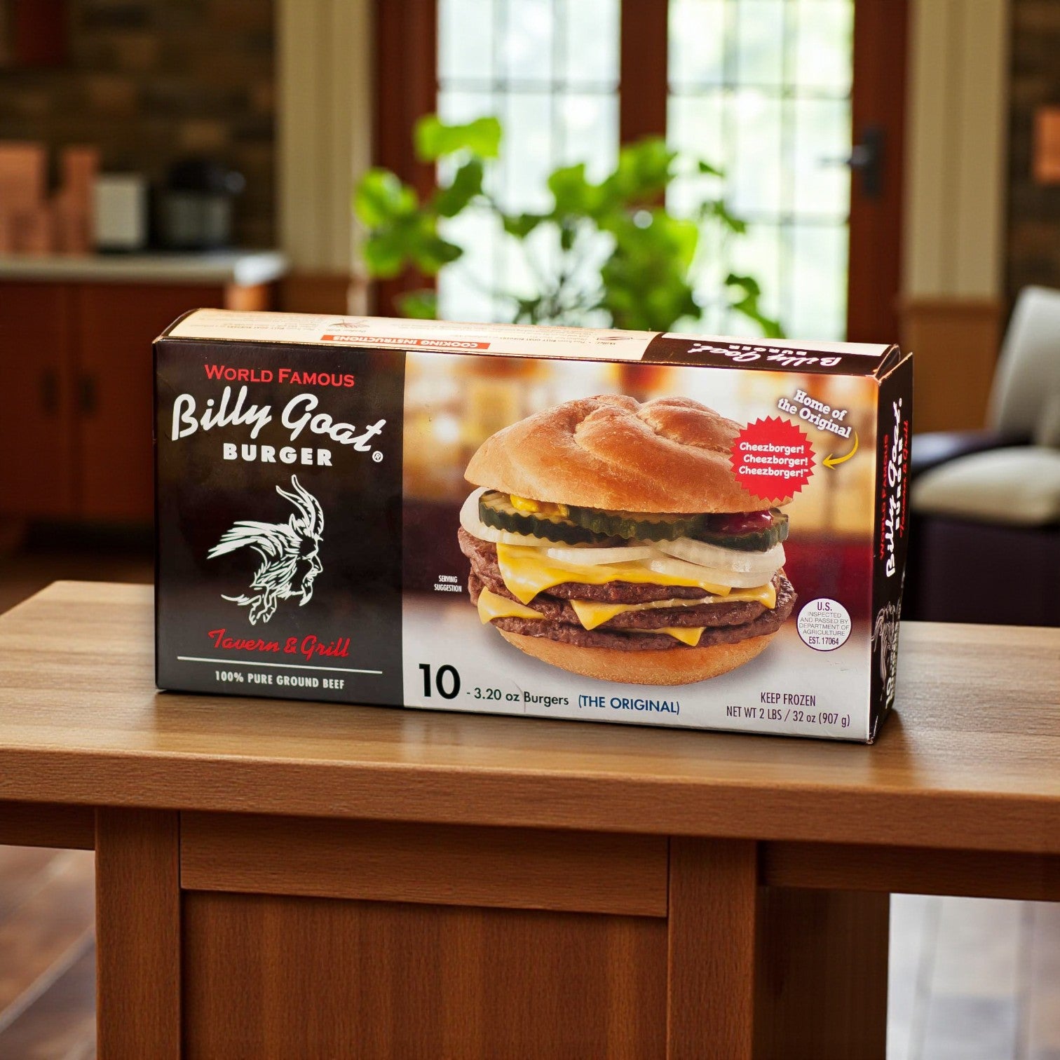 A box of Vienna Beef Billy Goat Tavern Burger Combo, featuring S. Rosen’s Kaiser Buns and Vienna Dill Chips, sits on a wooden table with a kitchen backdrop—perfect for enjoying a classic Chicago burger experience at home.
