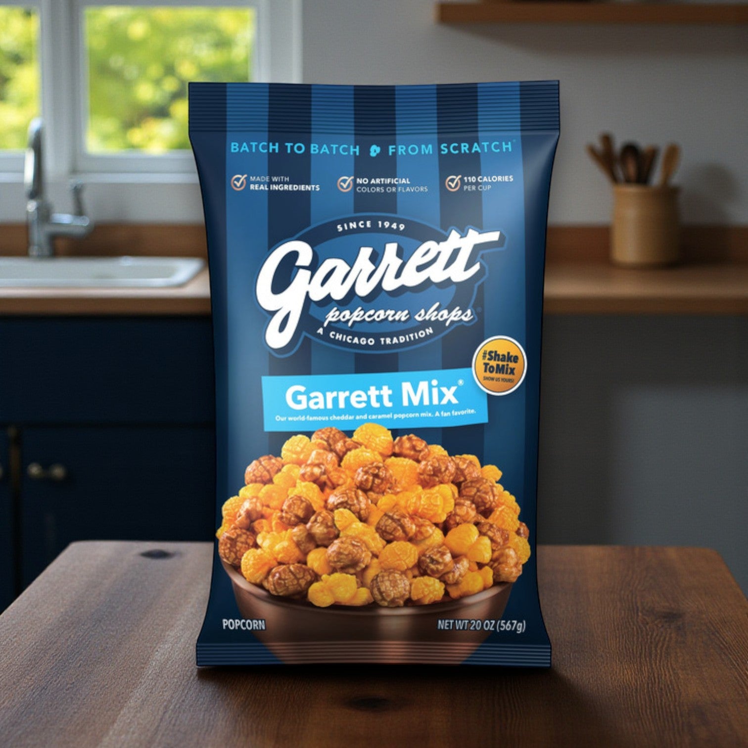 A bag of Fannie May Chicago Favorites Sweet & Savory Combo – Pixies Chocolate & Garrett Popcorn Mix sits on a wooden table, with caramel and cheese popcorn visible on the package.