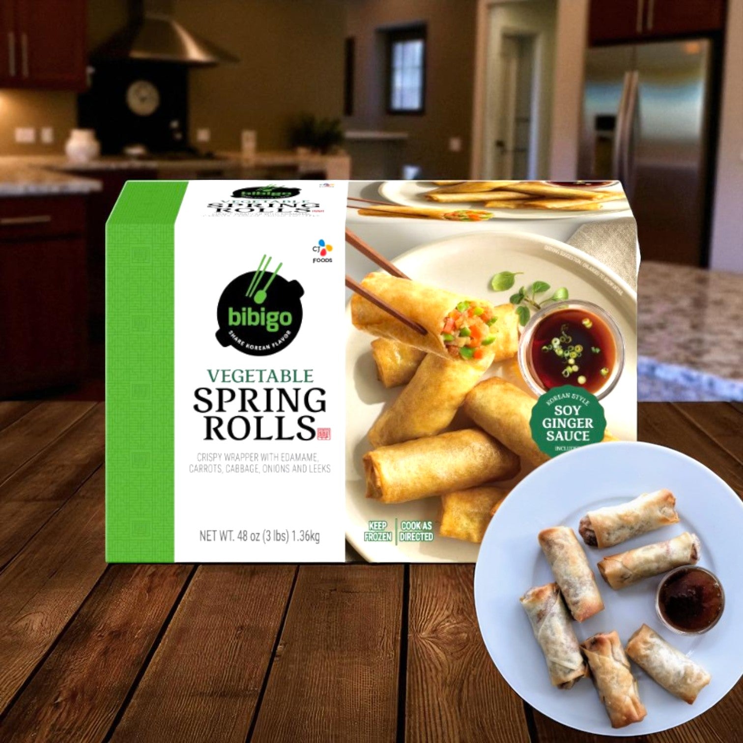 A box of Bibigo Vegetable Spring Rolls, 1 Pack, from Bibigo rests on a kitchen table beside a plate of six cooked vegetable spring rolls with soy ginger sauce in a cozy home setting.
