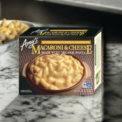 A single box of Amy's Macaroni & Cheese-1 Count, crafted using organic pasta and creamy cheddar cheese, rests on a marble surface. The packaging showcases an appetizing image of this quick meal dish.