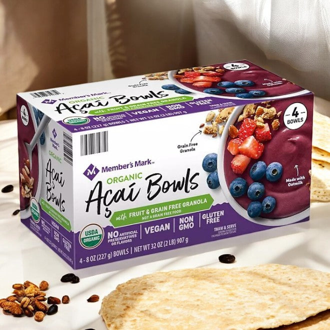 A box of Member's Mark Organic Acai Bowl, Frozen, 4 ct. is placed on the table. The packaging highlights its vegan, organic, non-GMO, and gluten-free benefits, showcasing the brand's dedication to affordability while featuring premium fruit and grain-free granola in each bowl.