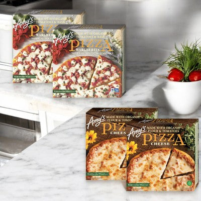 Boxes of Amy's Pizzas, featuring 2 Cheese Pizzas and 2 Margherita Pizzas for a total of 4 pizzas, are displayed on a marble countertop in a kitchen setting.