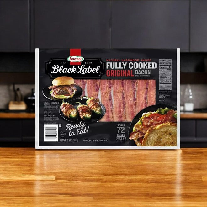 Hormel Black Label Fully Cooked Bacon 10.5 oz, 72 ct, sits on a wooden kitchen counter with dark cabinets, providing a convenient option for those seeking premium pork minus the effort.