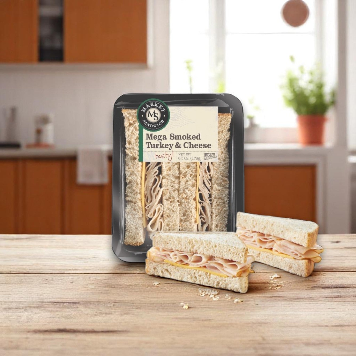 The E.A. Sween Mega Smoked Turkey & Cheese Sandwich Wedge – 6.3 oz (Individually Wrapped) sits on a wooden table, sliced in half with a kitchen background—ideal for any sandwich bundle or paired with wraps and subs.