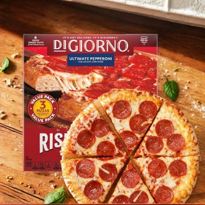 A DiGiorno Original Rising Crust Pepperoni Pizza, from a box containing three frozen pizzas, is shown in front of its packaging. The pizza, made by DiGiorno with quality ingredients, is sliced into eight pieces and generously topped with pepperoni.