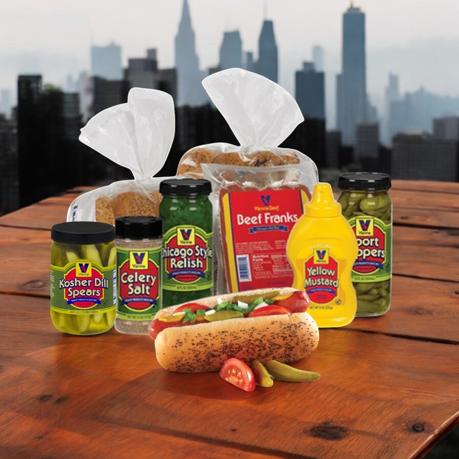 A Vienna Beef Hot Dog Kit, featuring 16 Chicago Style hot dogs with buns and condiments, sits on a wooden table beside jars of kosher dill spears, celery salt, relish, mustard, with a city skyline in the background.