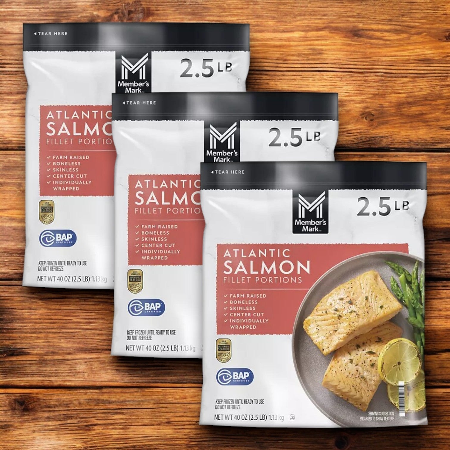 Three bags of Member's Mark Atlantic Salmon Fillet Portions, rich in Omega-3s, rest on a wooden surface. Each pack contains 4 oz fillets and is adorned with an image of salmon garnished with lemon and herbs, sourced sustainably for a mindful choice. Plus, enjoy free shipping!.