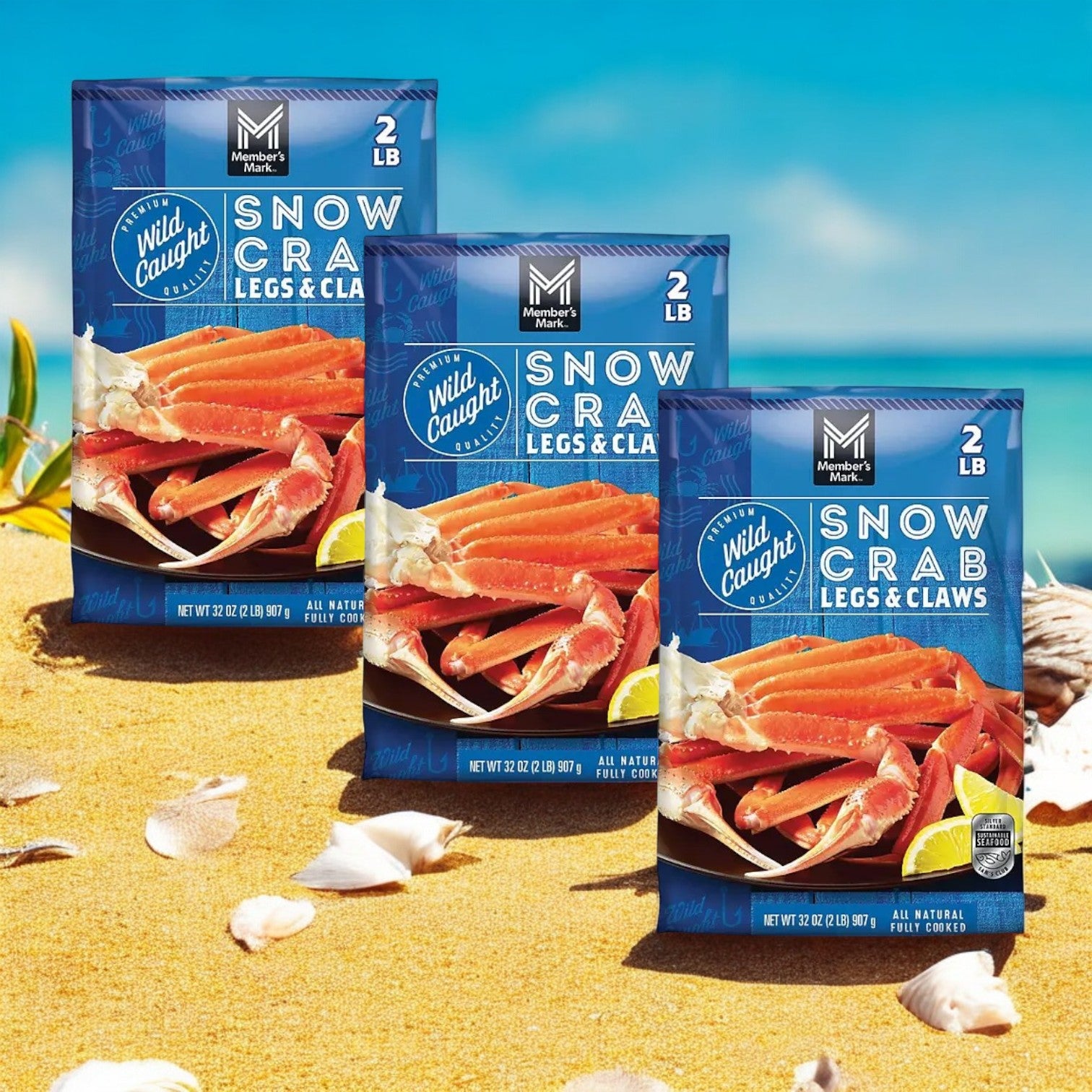 Three packages of Member's Mark Snow Crab Legs and Claw- 3 Count, each weighing 2 pounds of North Atlantic wild-caught snow crab legs and claws, are elegantly displayed on a sandy beach with seashells and seaweed.