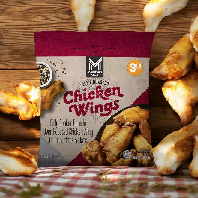 A case of Member's Mark Oven Roasted Wings, featuring juicy pre-cooked wings perfectly enclosed in a 3-pound package, is depicted amid cooked chicken atop a checkered tablecloth. The packaging showcases images of drumettes and flats, providing a tasty and healthy option for any gathering.