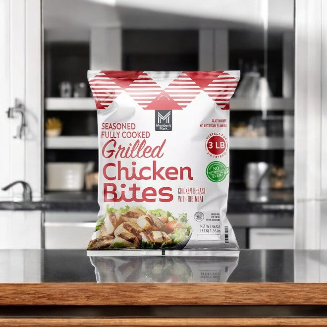 A 3-pound package of Member's Mark Grilled Chicken Bites, frozen and fully seasoned, rests on the kitchen counter, highlighting its premium ingredients. The packaging features nutritional details next to an appetizing image of the chicken enhancing a fresh salad.