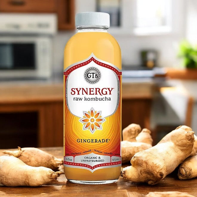 An 18-pack of GT's Organic Raw Kombucha Gingerade, from the brand Gt's, is arranged on a wooden table alongside fresh ginger pieces, bringing a zesty probiotic touch to your kitchen setting.