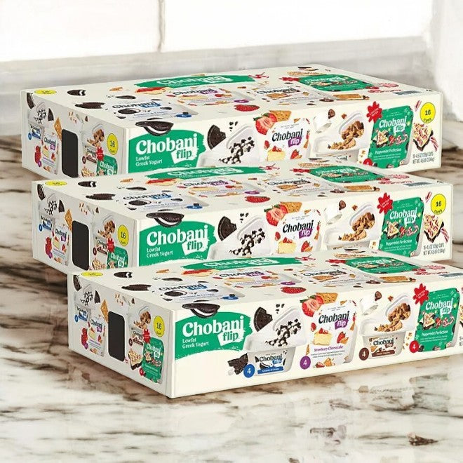 Three cases of Chobani Flip Lowfat Greek Yogurt, from the brand known for high-protein snacks, are stacked on a marble surface. Each case offers a variety of flavorful options.