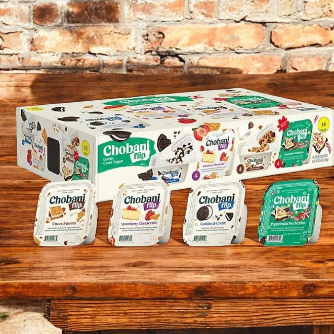 A Chobani Flip Lowfat Greek Yogurt Variety Pack, 4.5 oz, 16 count is elegantly showcased on a wooden table with a rustic brick wall backdrop.