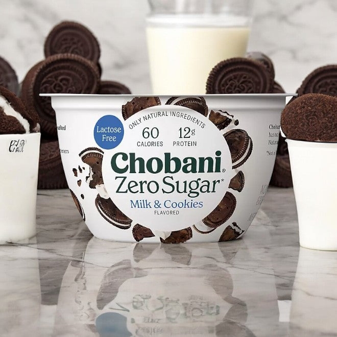 The Chobani Zero Sugar Nonfat Blended Greek Yogurt from the variety pack is shown with Oreo-like cookies and milk glasses on a marble countertop.