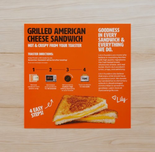 Lily's Toaster Grills Grilled Cheese Box- 1 Box, featuring detailed preparation instructions and vibrant promotional text on a wooden surface. Ideal for anyone in search of a quick and convenient meal option, these tasty frozen treats from Lily's make it easy to relish classic grilled cheese sandwiches in just minutes.