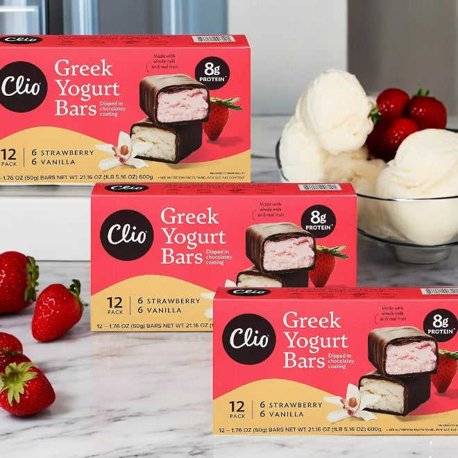 Three boxes of Clio Greek Yogurt Bars, each containing 12 strawberry and vanilla bars, are displayed with fresh strawberries and a bowl of yogurt.