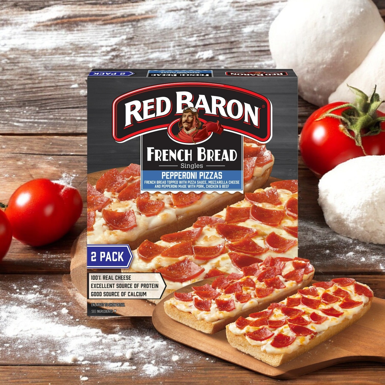 Red Baron Pepperoni French Bread Personal Frozen Pizzas, 10.8 oz, 2 Pack, rest on a wooden surface with fresh tomatoes, dough balls, and flour. These classic crust pizzas deliver an authentic pepperoni taste in a convenient frozen option from Red Barron.