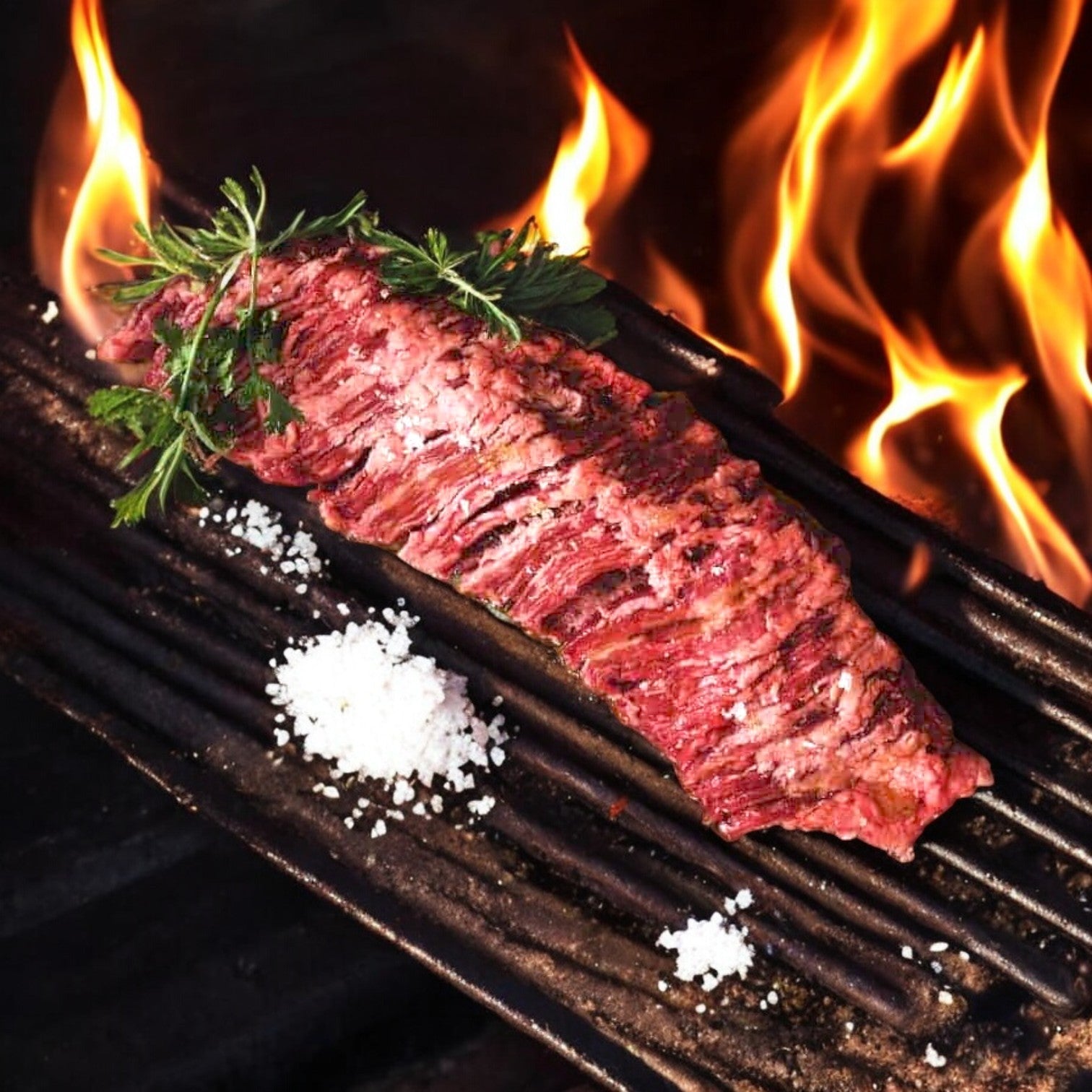 A Mino Prime Steaks – One Skirt Steak sizzles on the grill, tantalizingly seasoned with herbs and coarse salt over open flames.