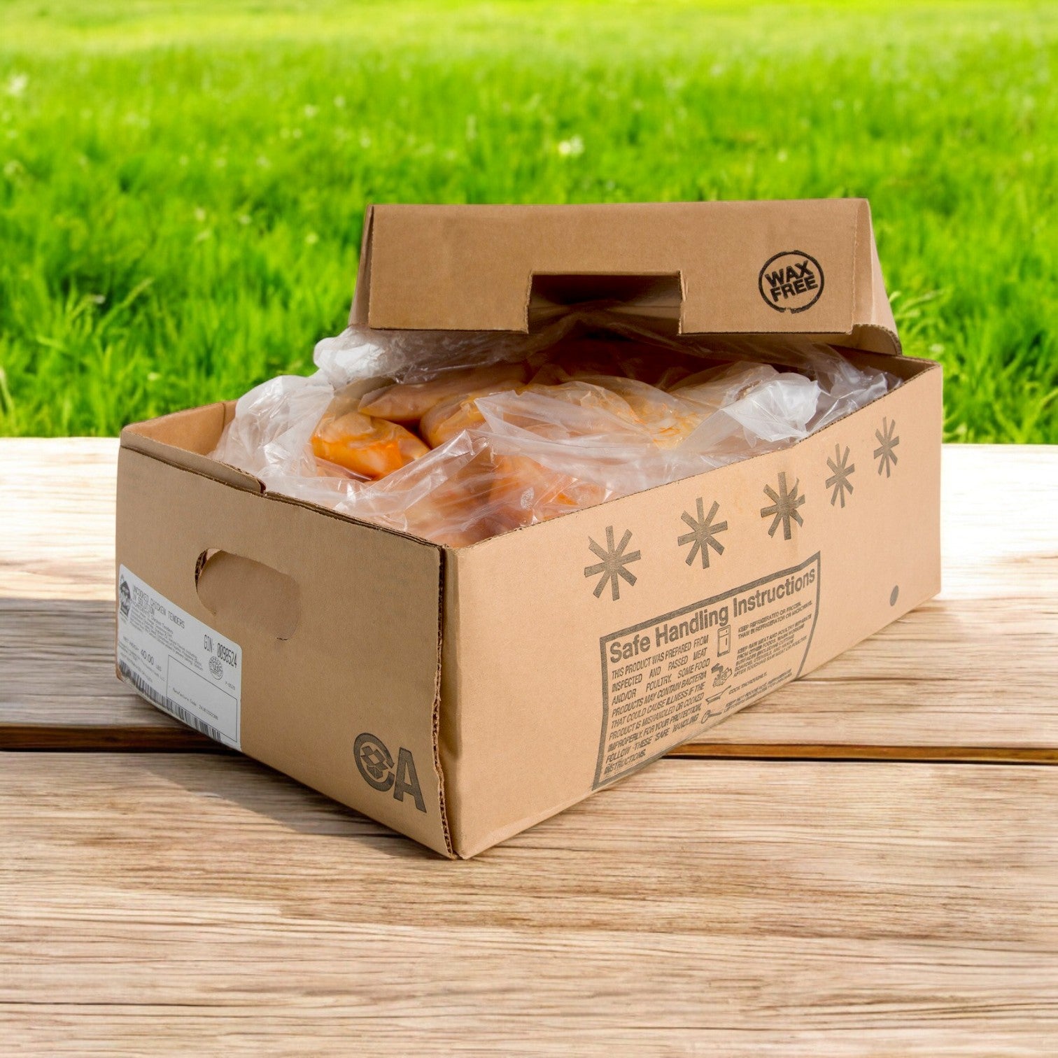 On a wooden surface with grass in the background, a cardboard box holds wax-free peaches in a plastic bag beside Sysco's Krispy Krunchy Piz&Chk Halal Frozen Chicken Tender for a deliciously diverse offering.