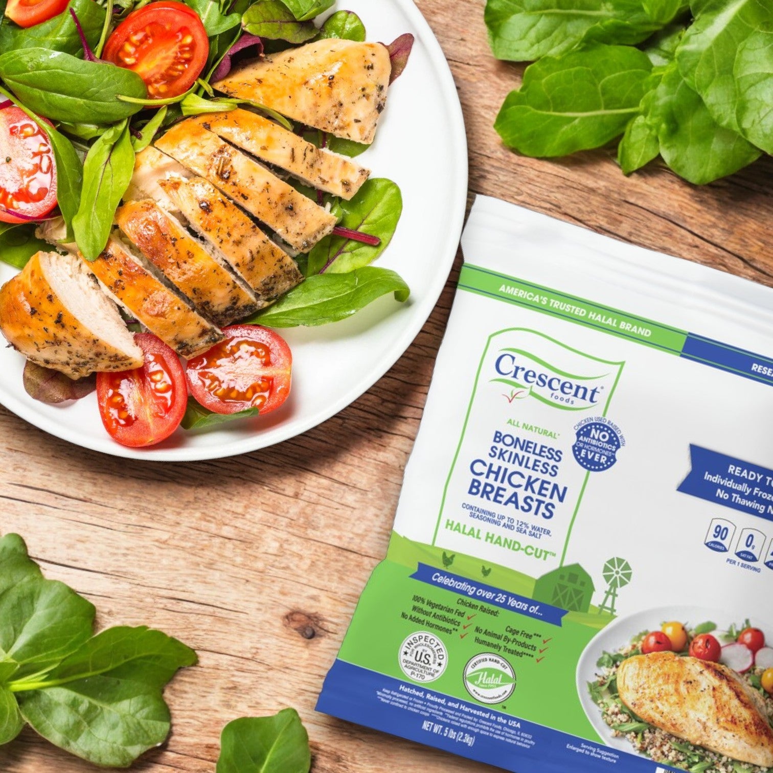 Sliced grilled chicken breast with salad on a plate, complemented by a pack of Crescent Foods All Natural Chicken Breasts - Boneless Skinless, Halal Hand-Cut (5 lbs) on a wooden surface.