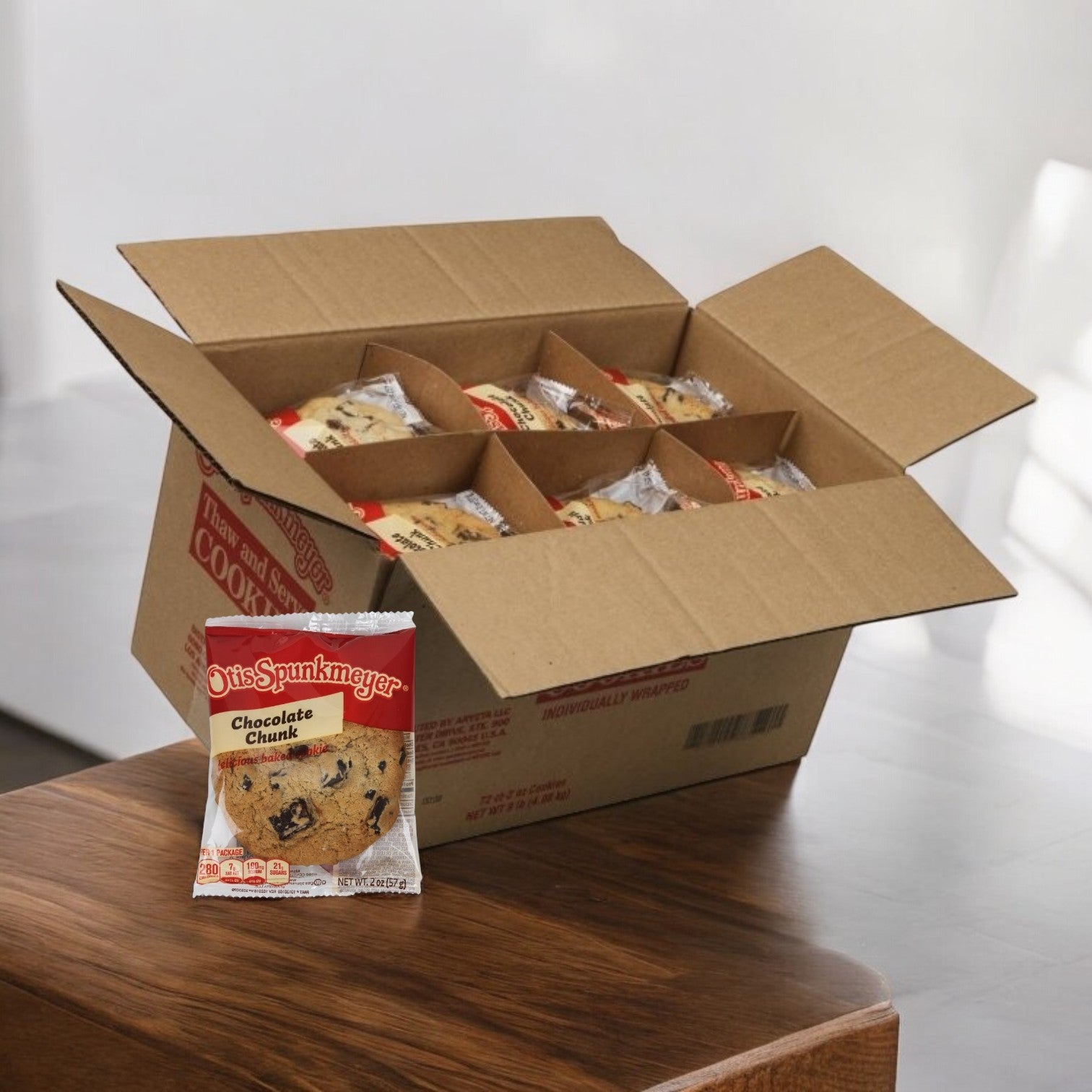 An open box of Otis Spunkmeyer cookies sits on the table, revealing several individually wrapped Chocolate Chunk 2 oz. Cookies from the 72-count package inside.