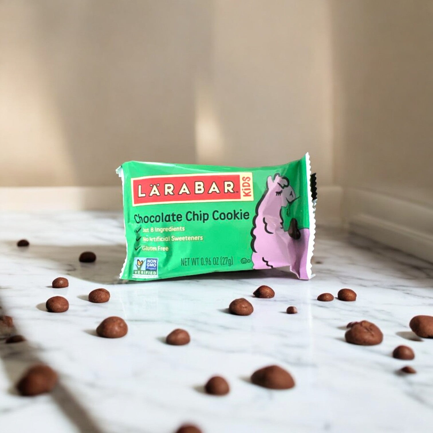 A Larabar Kid Gluten Free Bar Chocolate Chip Cookie, 1.6 oz - 1 Count, on a marble surface, with scattered chocolate chips around it, offers a wholesome and nutritious snack that's perfect for those embracing clean eating principles.