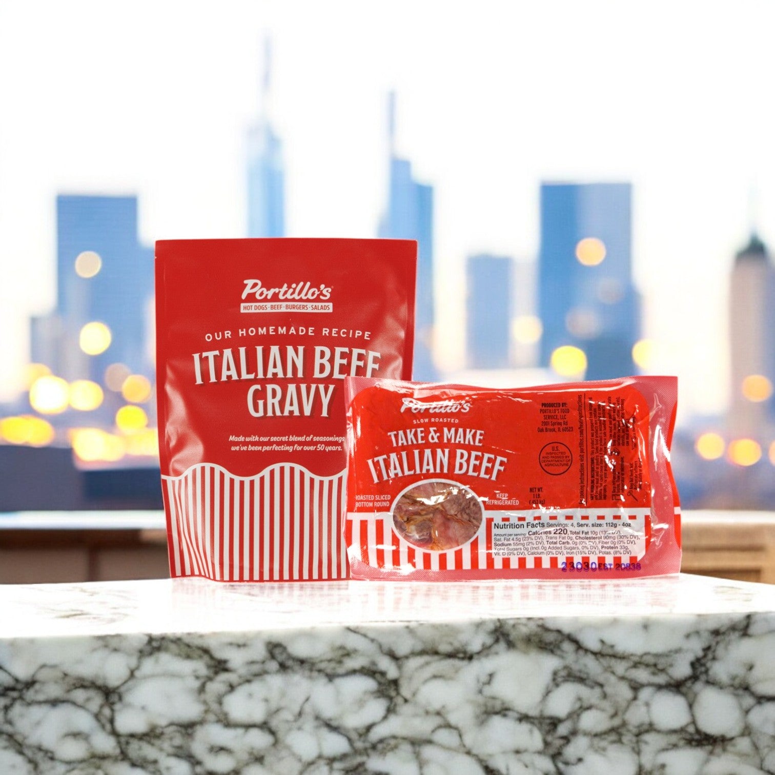 Portillo's Italian Beef Gravy and Take & Make Italian Beef (1 lb Beef and 30 oz. Gravy) are displayed on a marble countertop, ready for authentic Chicago-style sandwiches, with a blurred cityscape in the background.