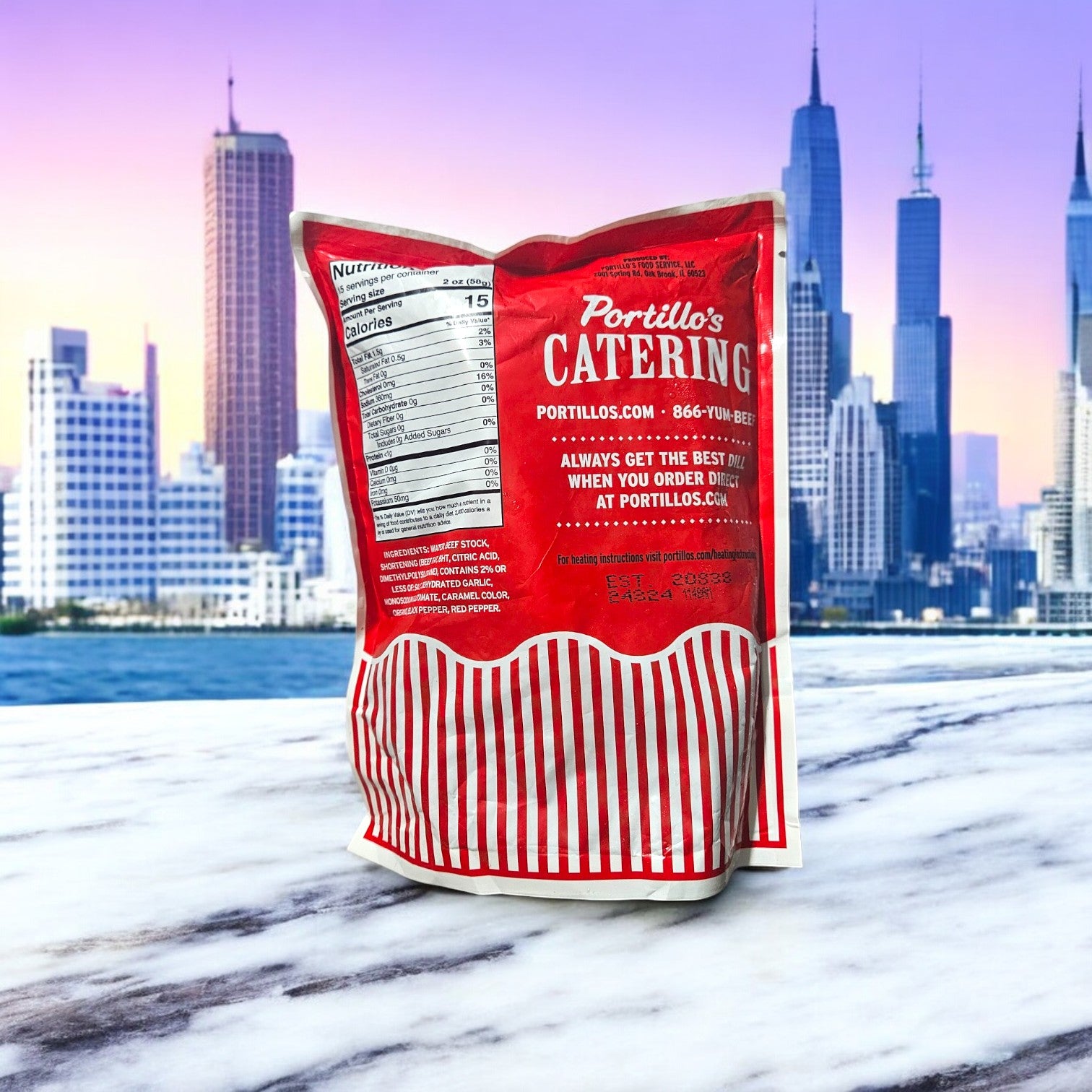 A Portillo's Catering bag showcases the tempting "Portillo's Italian Beef Gravy! Take & Make" featuring 1 pound of beef and 30 oz. of gravy, elegantly placed on a marble surface with Chicago's skyline in view.