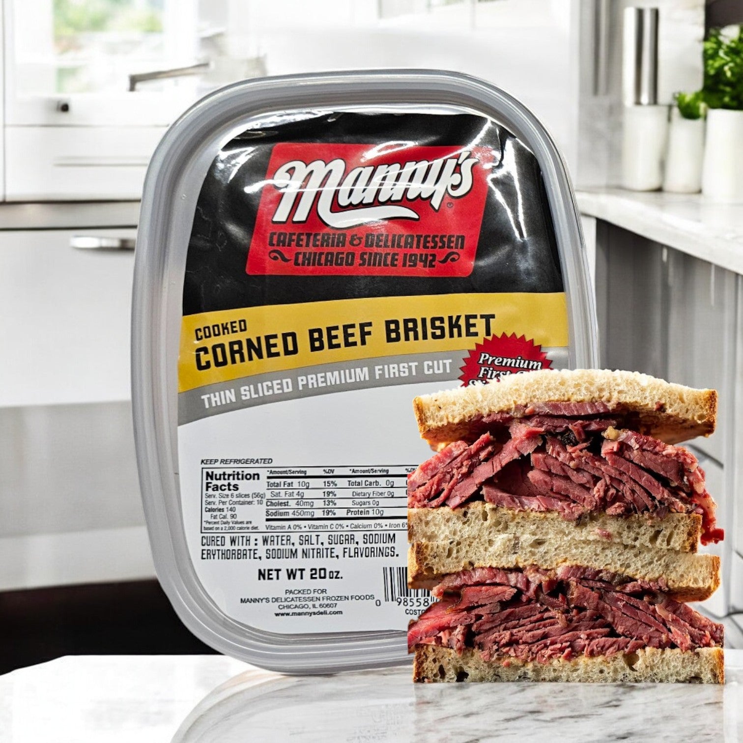 A container of Manny's Cooked Corned Beef Brisket-1 Count rests by a sandwich, built with tender brisket slices and freshly baked bread, artfully laid out on the kitchen counter.