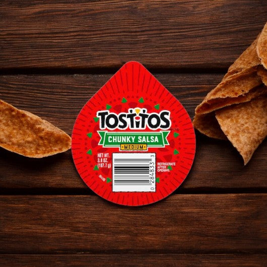 A portable snack, this single-serve 3.8 oz container of Tostitos Medium Chunky Salsa Dip invites you from a wooden surface next to several tortilla chips.