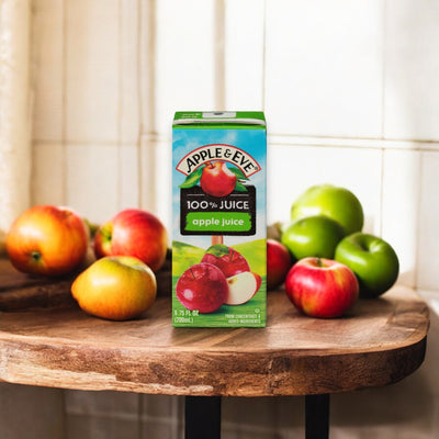 A carton of Apple & Eve apple juice, specifically the Adam and Eve Apple Juice in an apple flavor, 6.75 fl oz - 1 count, is placed on a wooden surface surrounded by red and green apples.