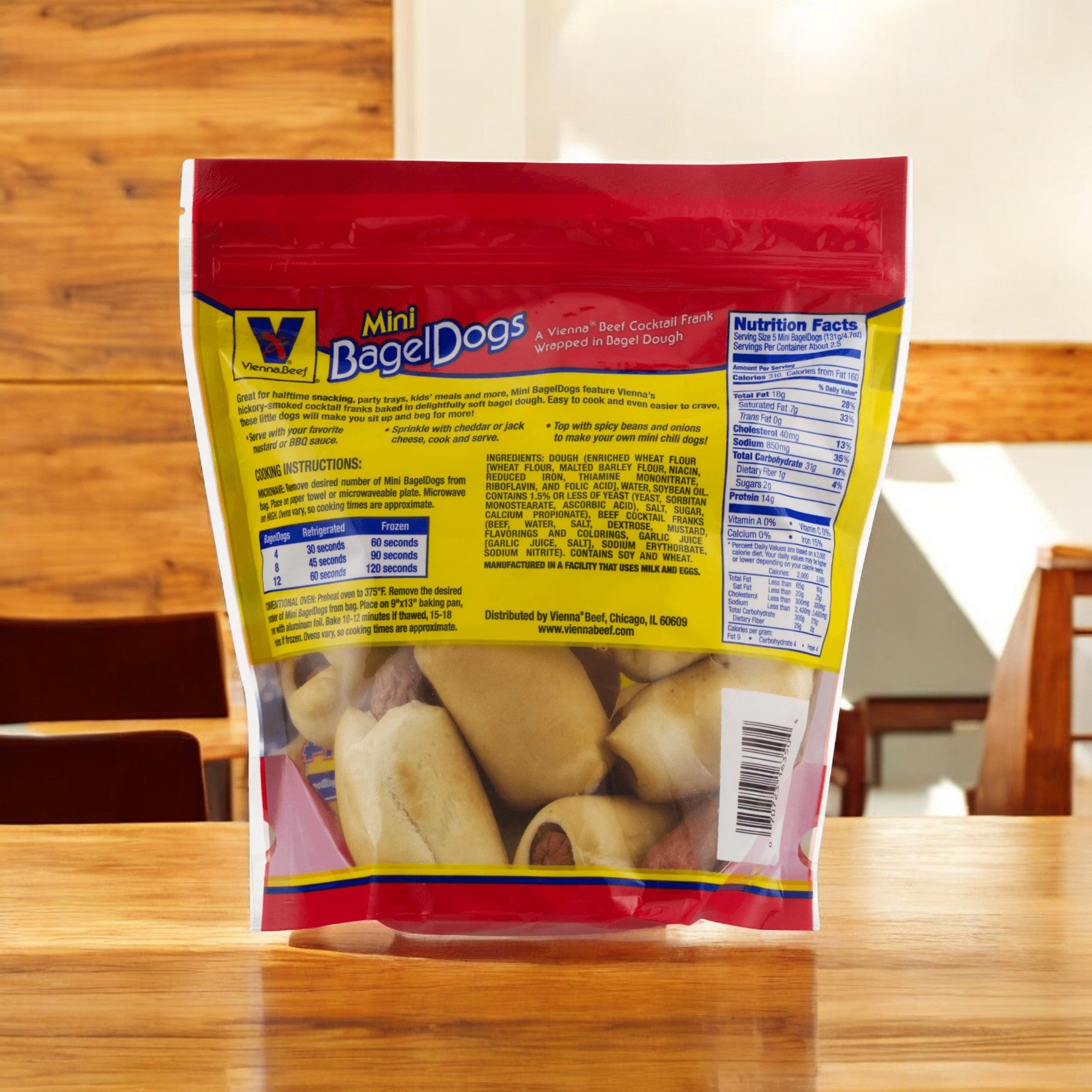 A package of Vienna Beef Natural Mini Bagel Dogs, 12 oz, rests on a wooden table. The bag prominently features nutritional information, cooking instructions, and a product image on the front, making it an ideal snack option with all-natural beef.