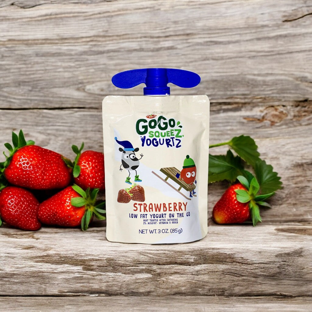 A GoGo squeeZ® yogurtZ - Strawberry 3 oz pouch from Gogo Squeez is placed upright on a wooden surface next to some fresh strawberries, offering a nutritious on-the-go snack that's perfect for any time of day.