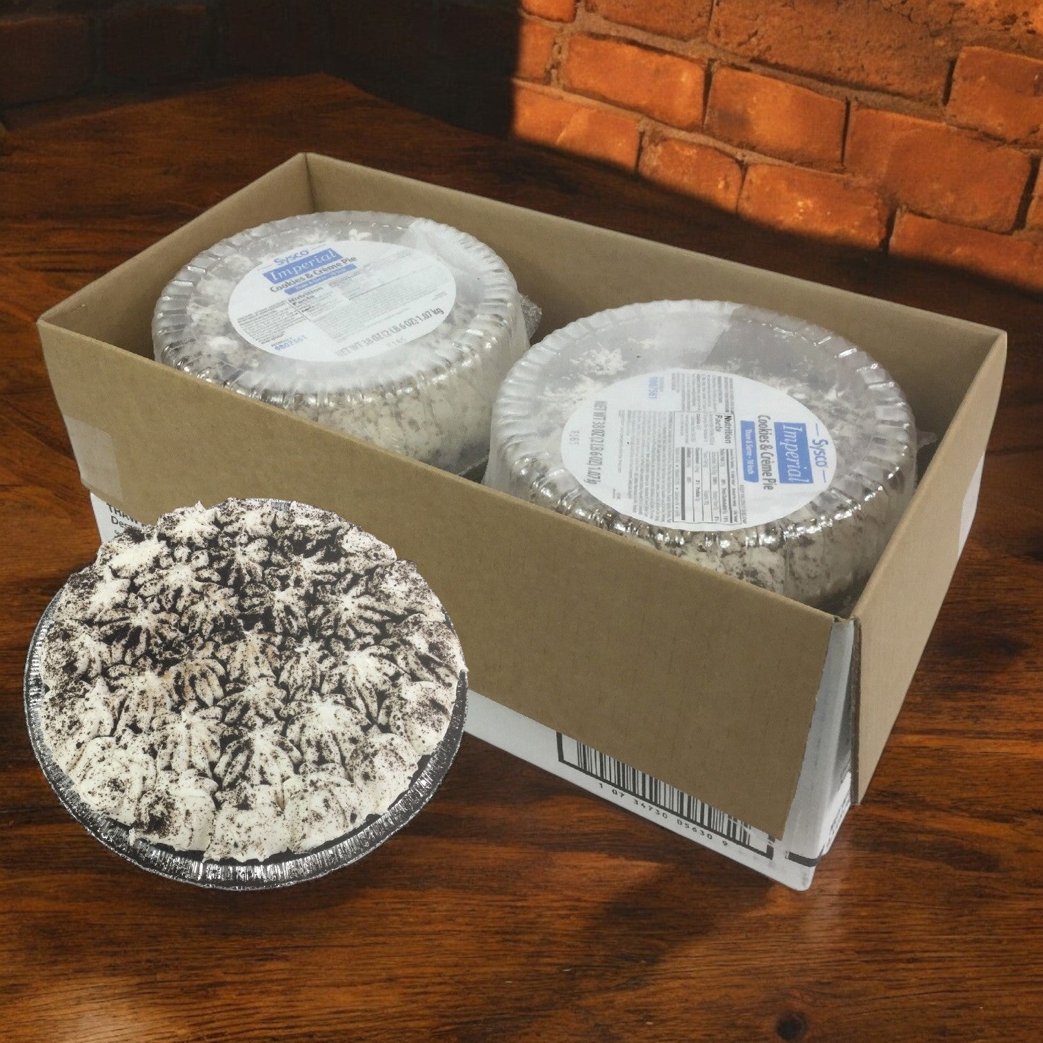 Two 10-inch Sysco Imperial Cookies & Cream Pies are nestled in a cardboard box, ready to satisfy your dessert cravings. One luscious pie sits invitingly on a wooden surface, perfect for a quick thaw and serve delight. Each case contains 4 pies for all your sweet needs.