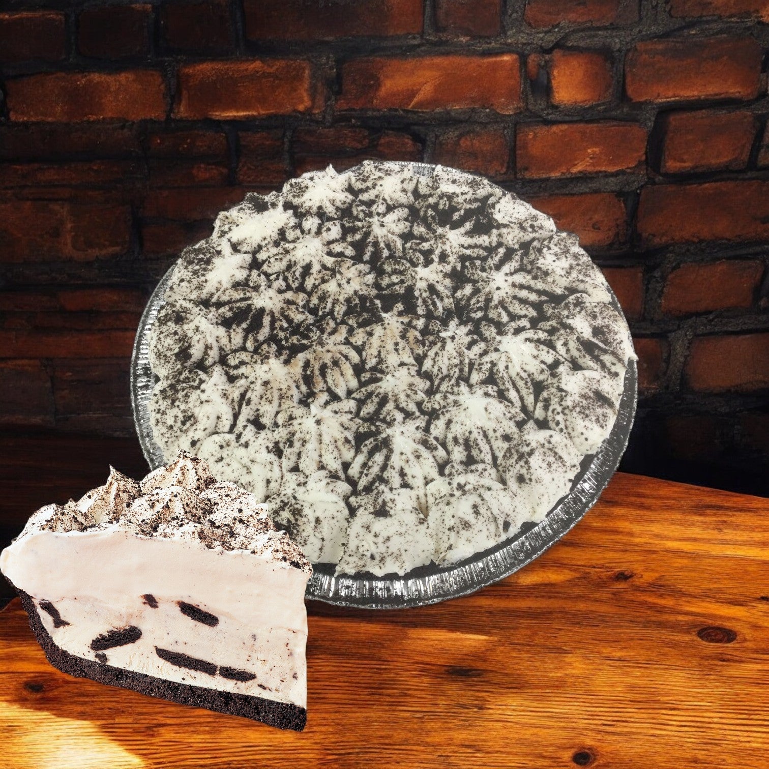 A Sysco Imperial Cookies & Cream Pie sits on a wooden table, with a slice revealing creamy filling and cookie pieces against a brick wall backdrop. This 10-inch thaw & serve pie from a 4-pie case is perfect for satisfying dessert cravings.