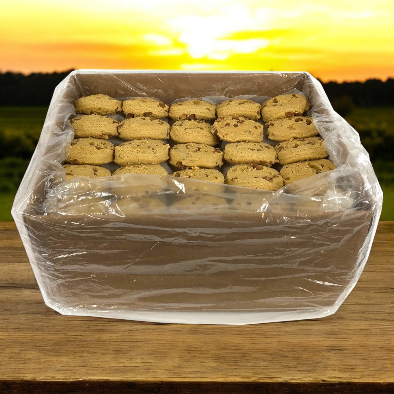 A box of David's Peanut Butter cookies wrapped in clear plastic from David's Cookies, perfectly stacked on a wooden surface with a sunset in the background.