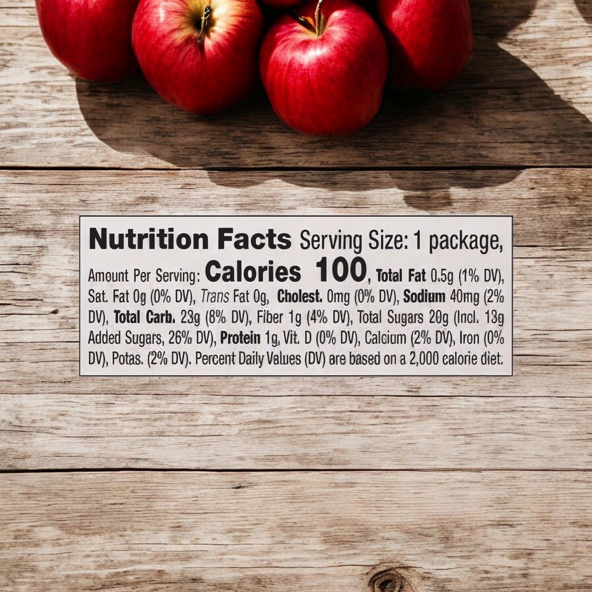 Dippin' Stix Fresh Gala Sliced Apples and Caramel alongside a nutrition facts label on a wooden surface. The label lists nutritional information for the product, which includes 100 calories, 0.5g total fat, 23g total carbs, 1g protein, and various vitamins and minerals.