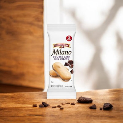 A package of Pepperidge Farm Milano Cookies, Double Dark Chocolate, stands on a wooden surface, surrounded by a few crumbs and pieces of chocolate, promising indulgence made from the finest quality ingredients.