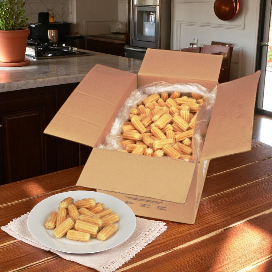 A large open case of Hola Churro® – Mexican Mini Churros (2", 500 count) by Hola Churro sits on a wooden table, with several delicious churros served on a white plate in front.