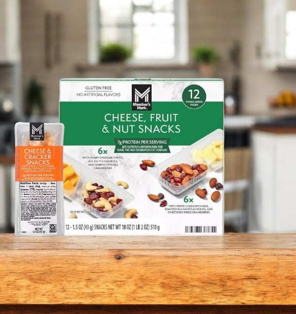 A box of Member's Mark Cheese, Fruit and Nut Snacks sits on a wooden countertop as a balanced option. A cheese and cracker pack is beside it against a blurred kitchen background, highlighting this healthy alternative to traditional snacks.