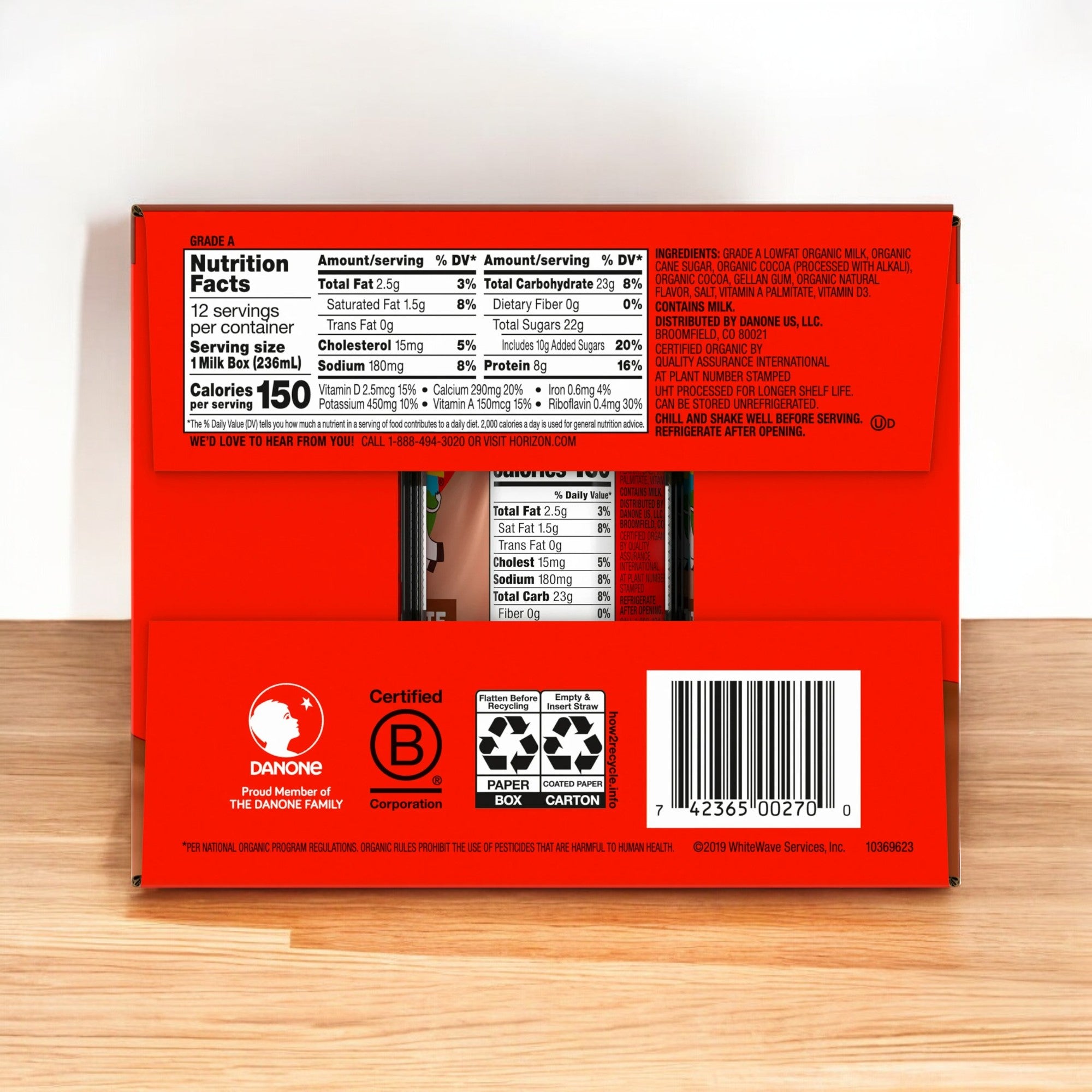 A red carton of Horizon Organic Shelf-Stable 1% Low Fat Chocolate Milk with visible nutrition facts, recycling symbols, a barcode, and the text "Easy Lunches" sits on a wooden surface. This convenient beverage is perfect for on-the-go moments.