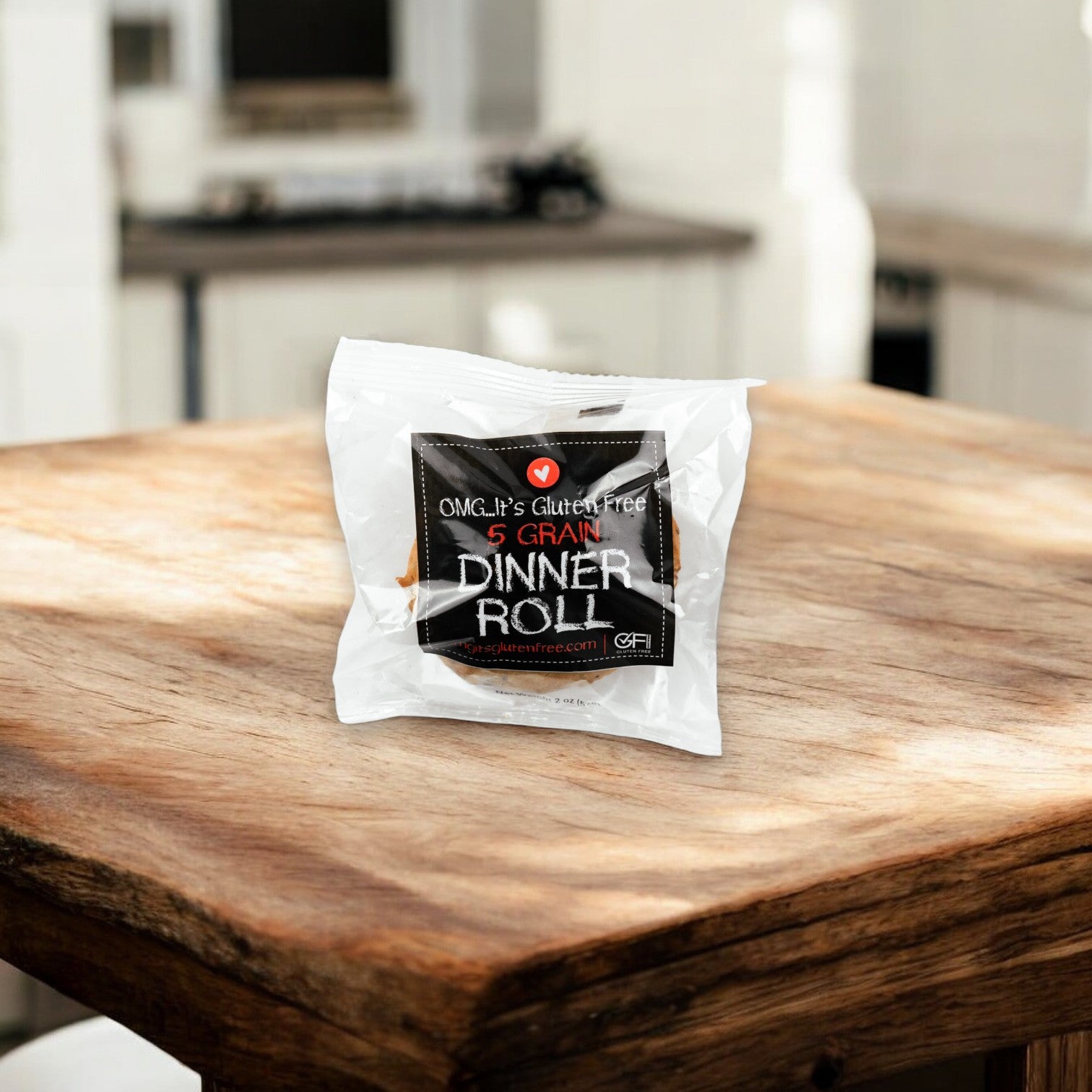 An OMG It's Gluten Free 5 Grain Dinner Roll, weighing 2 oz., is placed on a wooden table in a cozy kitchen setting.