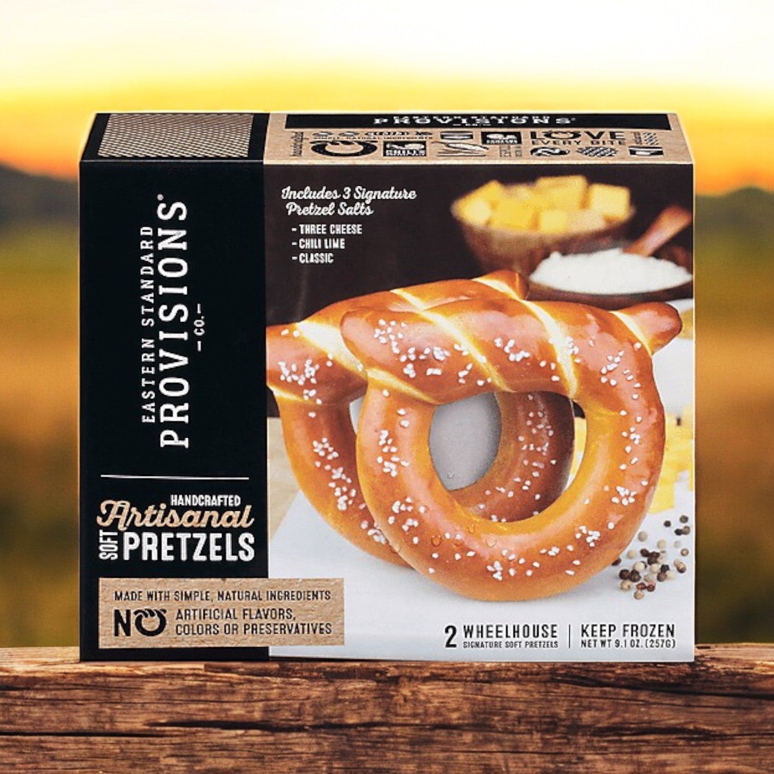 A box of Easy Lunches Eastern Standard Provisions Pretzels, Signature Soft, Artisanal, Handcrafted 2 ea - 3 Packs is pictured outdoors, showing two salted pretzels on the front of the packaging.