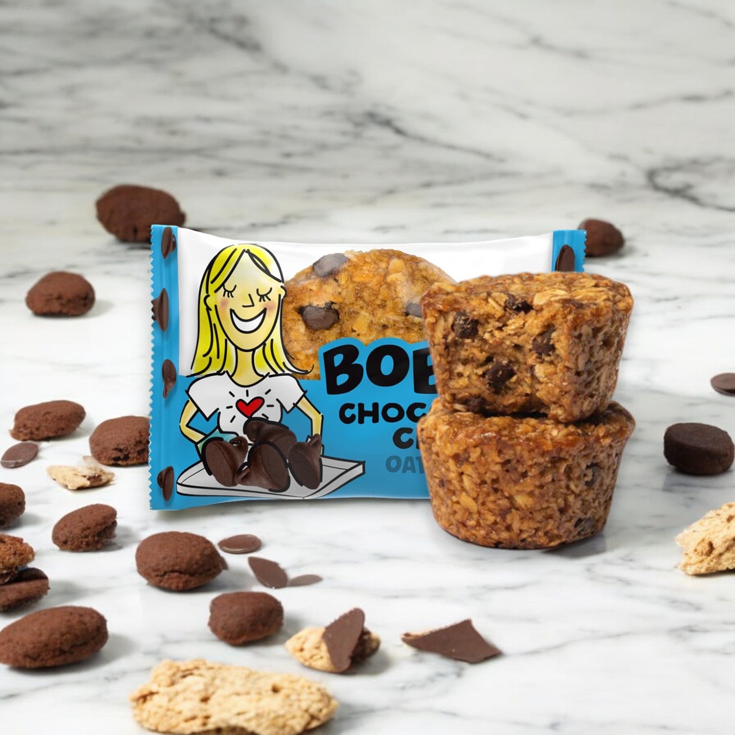 A packet of Bobo's Chocolate Chip Oat Bites, 1.3 oz - 1 Count, next to two stacked gluten-free oat bars on a marble surface, surrounded by chocolate chips and cookie pieces.