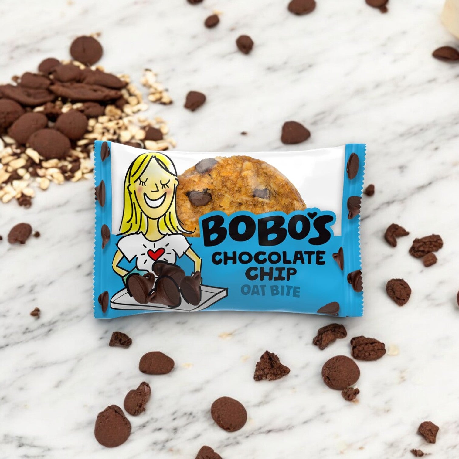 A package of Bobo's Chocolate Chip Oat Bites, 1.3 oz - 1 Count, on a marble surface with scattered chocolate chips, crumbled pieces, and gluten-free whole grain oats around it.