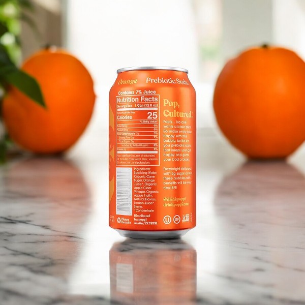 A can of Poppi Prebiotic Soda, Orange, 1-12 fl oz Can from the brand Poppi rests on a marble surface, with two whole oranges in the background. The nutritional information and product description on the can emphasize its healthy ingredients and low-calorie content.