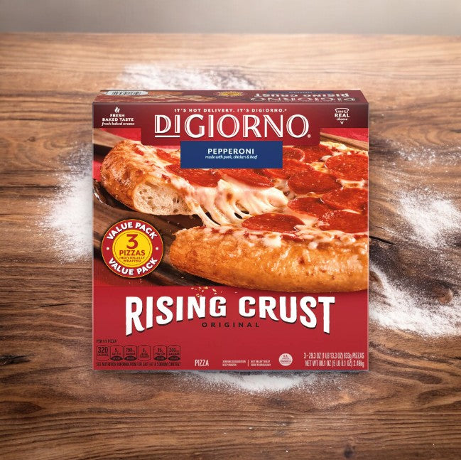 A DiGiorno Original Rising Crust Pepperoni Pizza value pack box that contains three frozen pizzas made with quality ingredients, displayed on a wood surface lightly dusted with flour.