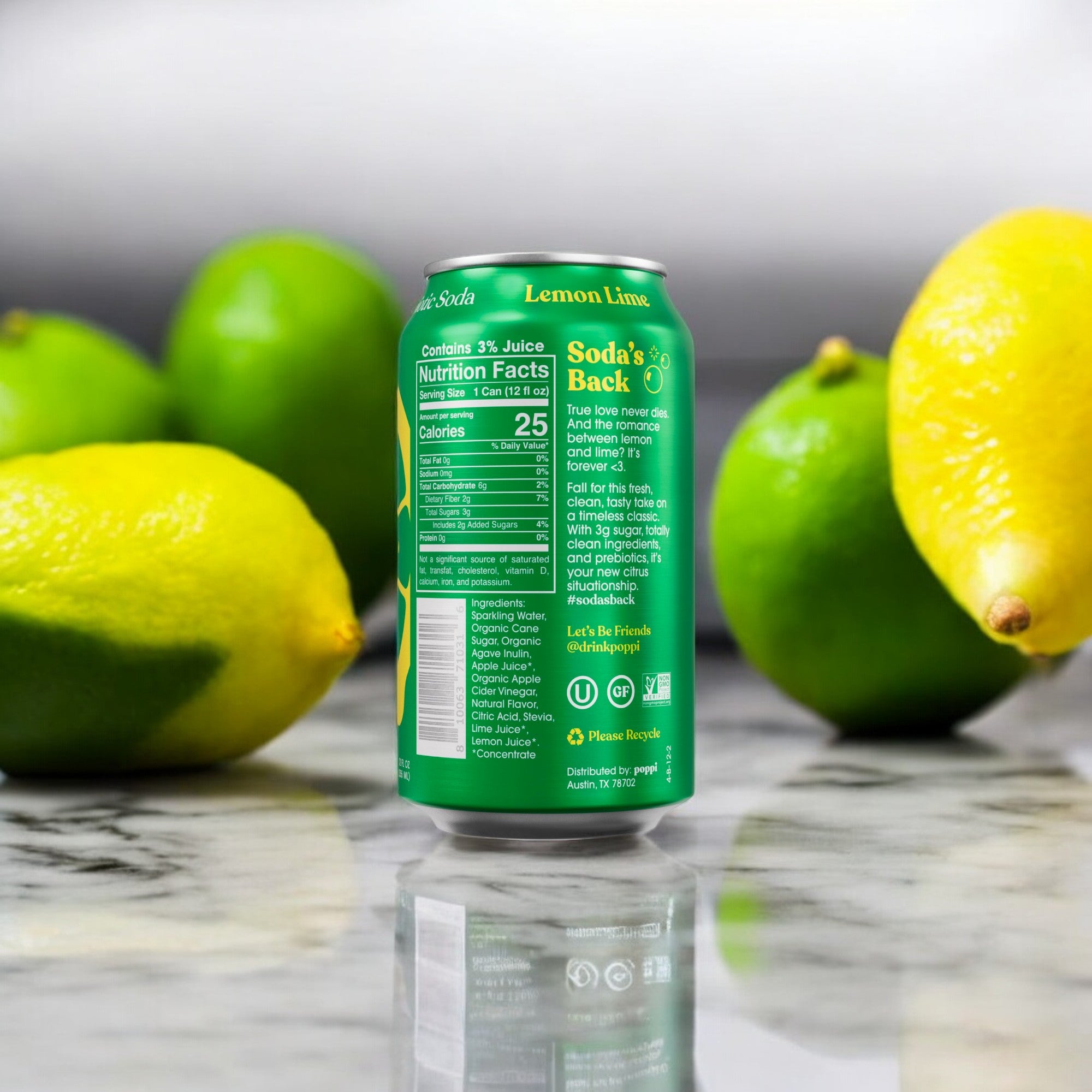 A can of Poppi Prebiotic Soda, Lemon Lime, with its green label showcasing nutrition facts and brand text, sits on a marble surface surrounded by fresh lemons and limes, evoking the refreshing feel of a new pitch on Shark Tank.