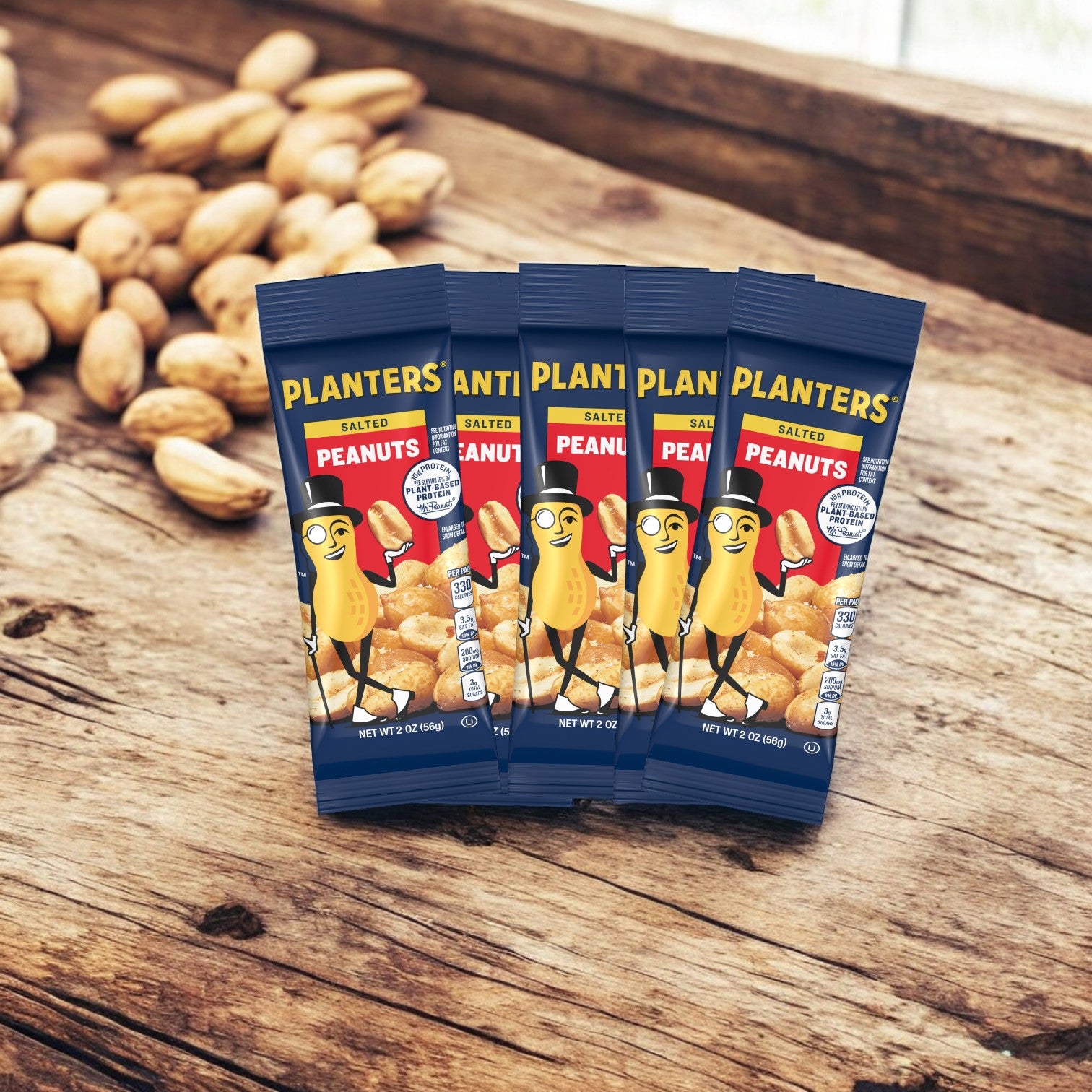 Four bags of Planters Peanuts are arranged on a wooden surface, with salted peanuts scattered in the background.