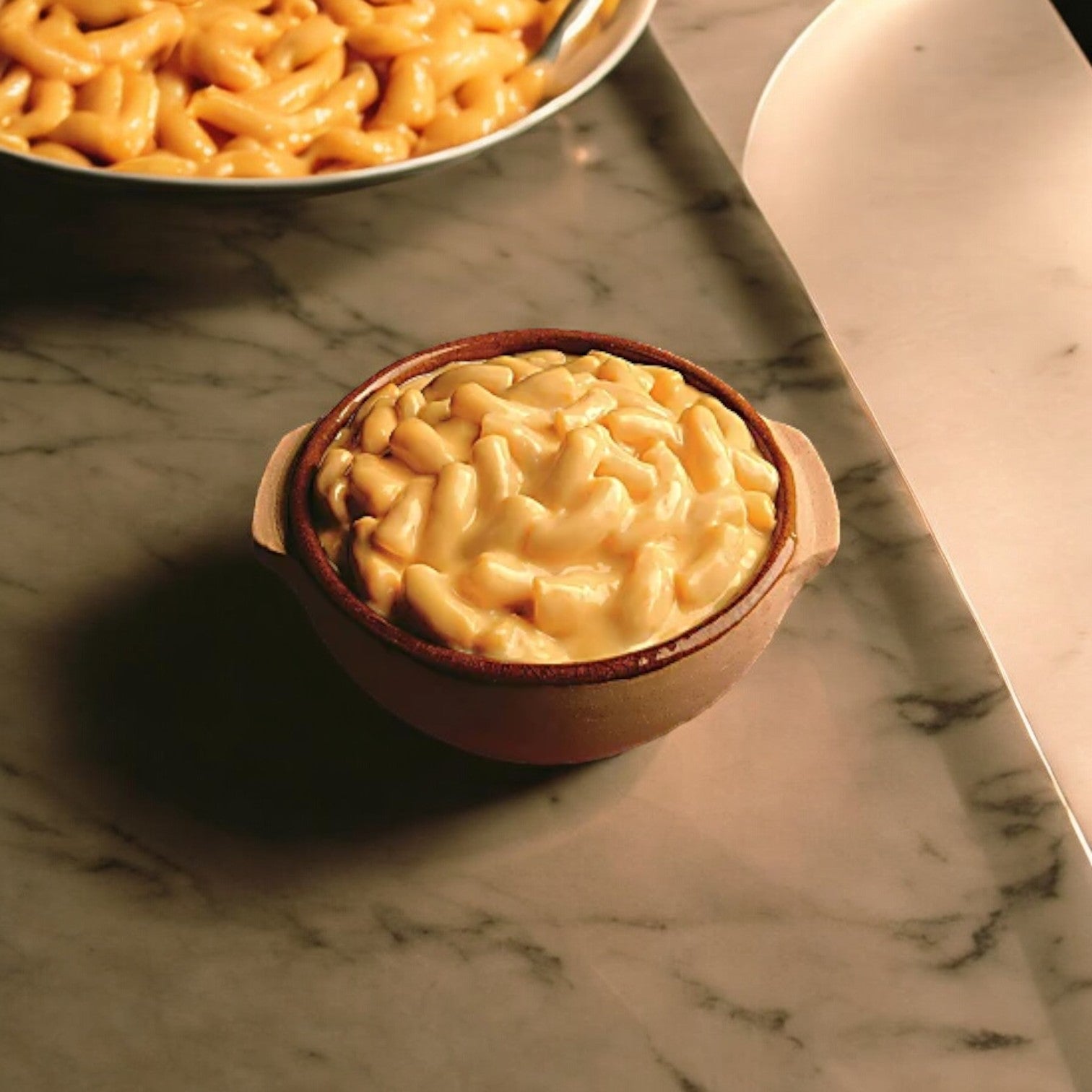 A bowl of creamy Amy's Macaroni & Cheese-1 Count by Amy's sits on a marble surface, with a plate of identical content partially visible in the background.